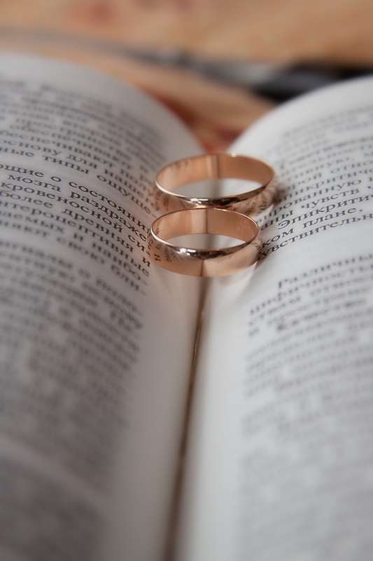 Обручальные кольца, выполненные в классическом стиле, на фоне страниц книги. - фото 675709 Фотограф Никитина Анастасия