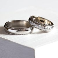 Обручальные кольца в классическом стиле. Выполнены из белого золота, женское кольцо украшено ниткой из 9 бриллиантов.