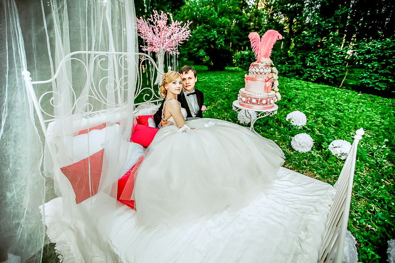Оформление летней свадебной фотосессии в парке: невеста и жених на кровати с белыми, красными подушками, белым балдахином, рядом - фото 1787973 Свадебное агентство "Scarlet Star" - Алая звезда