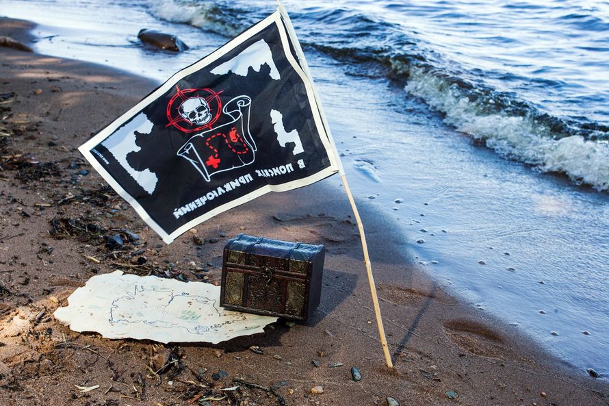На пляже возле моря, лежит коричневый сундук, пиратский флаг и карта - фото 2814145 autumn melody