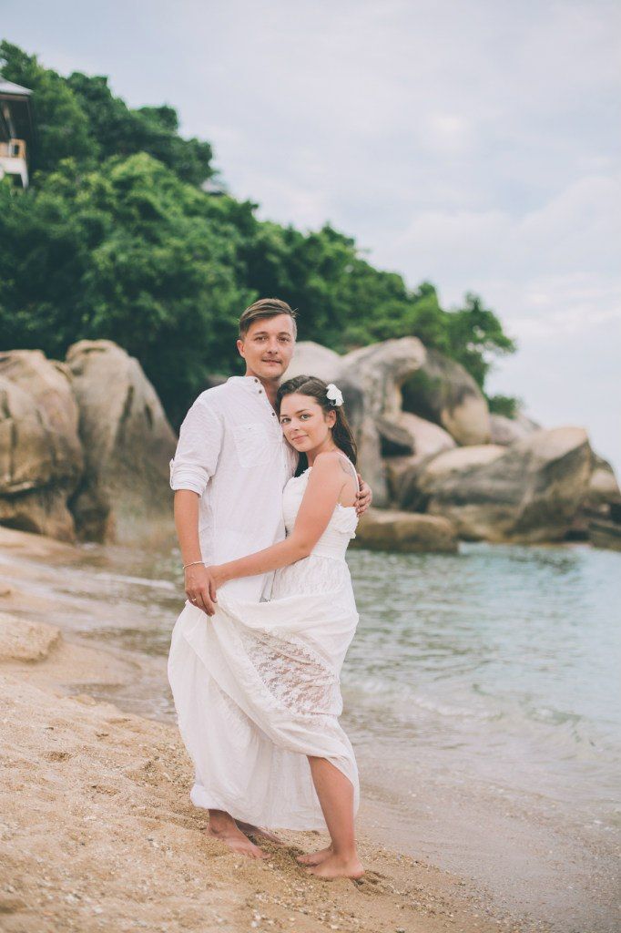 На пляже на фоне прибрежных камней стоят молодожены, жених  в белых брюках и рубашке, невеста в белом длинном платье с белым - фото 2983741 Фотограф Егорова Елена