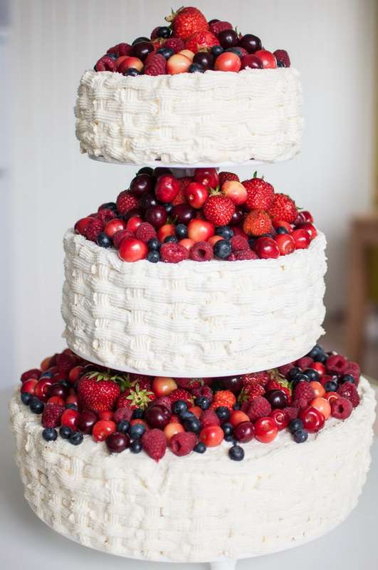 Многоярусный белый свадебный торт, украшенный ягодами и фруктами. - фото 2725579 Кондитерская студия Тортификация