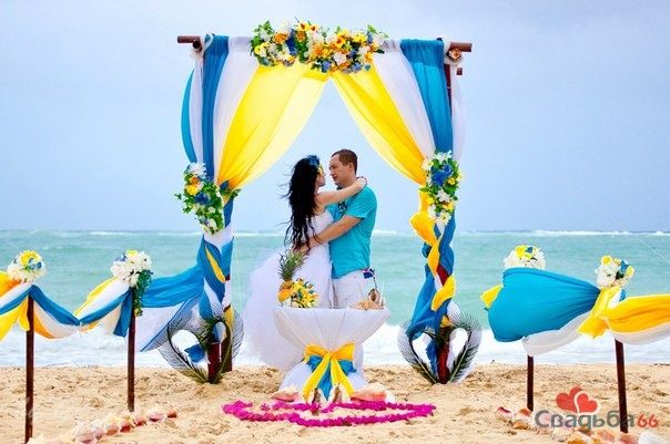 У свадебной арки, украшенной желтых и голубых тонах,стоят молодожены, заключив друг друга в объятьях, невеста в пышном белом - фото 2402098 Юлия163