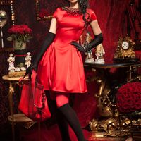 Подружка невесты в коротком атласном красном платье "принцесса" с маленьким рукавом, по вырезу горловины  декорированным черными камнями, в красных колготах, черных сапогах-чулках, длинных перчатках, черном берете держит сумку
