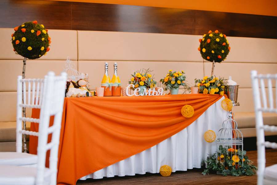 Стол, украшенный белой и оранжевой скатертями, букетами цветов и апельсинами - фото 3498999 galinkapotapova