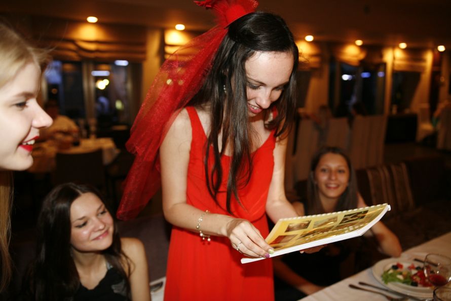 Будущая невеста в красном платье тематического стиля рассматривает подарок от гостей альбом для новорожденного. - фото 2918885 Ярослава Костина