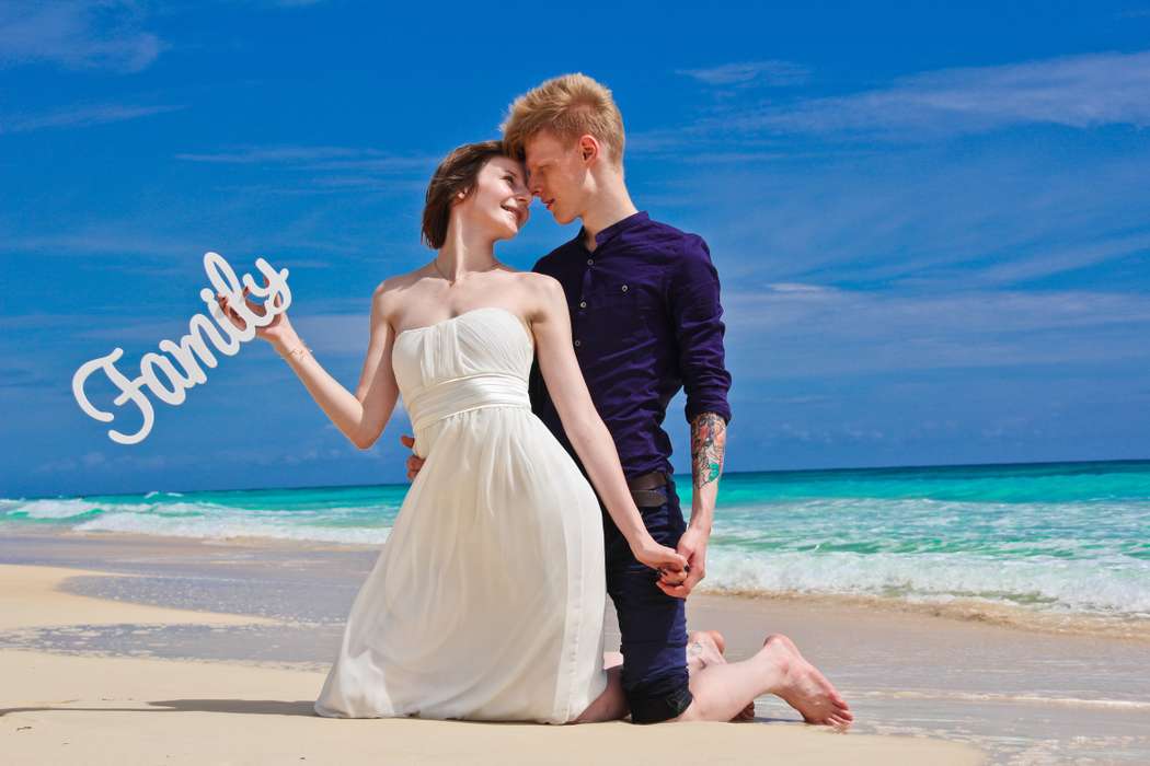 На лазурном побережье на коленях стоят влюбленные, невеста в белом открытом платье обернулась к жениху в синих брюках и рубашке, - фото 2730185 minina_katerina