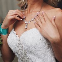 Невеста в платье, расшитом кружевом, пайетками, бисером и серебряном ожерелье с круглыми звеньями и подвеской из цирконов.