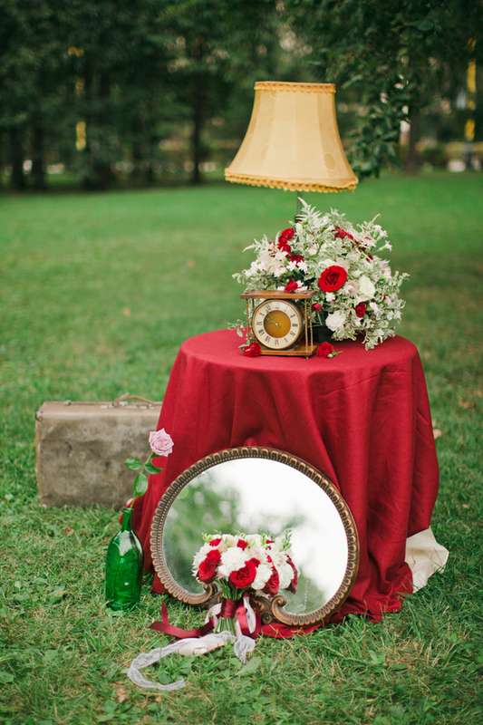 Маленький красный столик с букетом цветов, часами и лампой, рядом лежит зеркало - фото 2918205 Florence Flowers - флористы-декораторы
