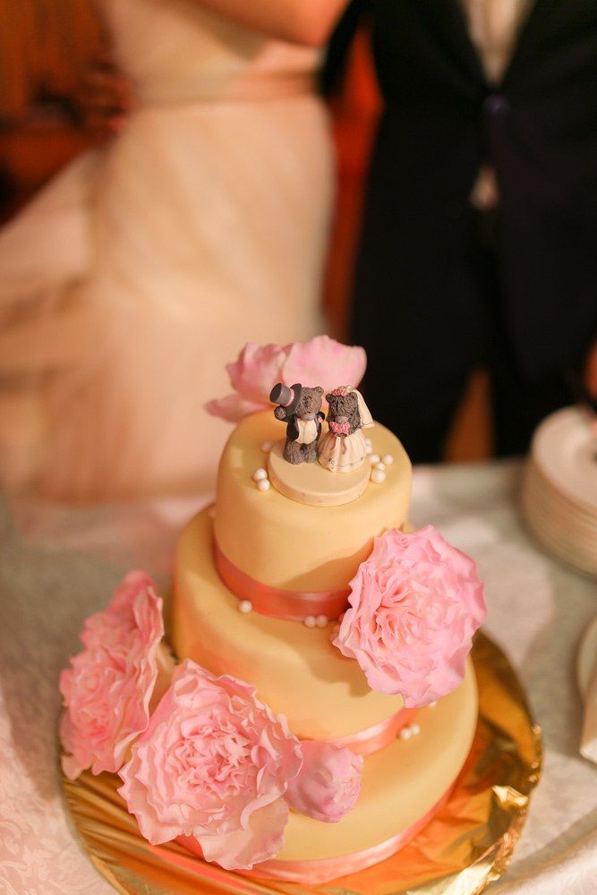 Трехъярусный торт желтого цвета украшенный розовыми ленточками и цветами, сверху фигурки жениха и невесты.  - фото 2826675 Chaashka