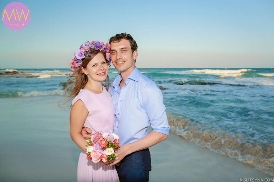 На песчаном пляже, наслаждаясь волнами прибоя, стоят влюбленные, жених в черных брюках и голубой рубашке держит за талию невесту - фото 2915509 My Wish - свадьба и фотосессии в Мексике