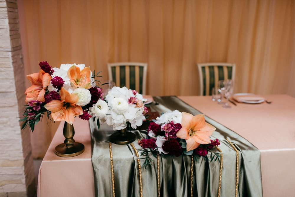 В зале стоит стол, украшенный розовой скатертью, на котором стоят цветочные оранжево-бордовые композиции - фото 3434729 Алена Шнайдер