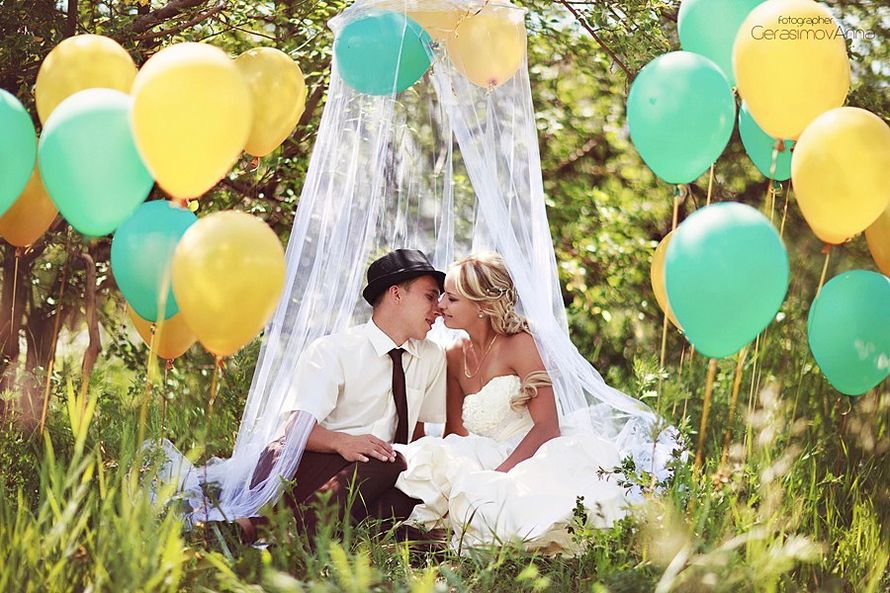 На фоне зелени и желто-голубых шаров, сидя на траве в белом шатре из прозрачной ткани, целуются жених и невеста - фото 3065527 Свадебный фотограф Анна Герасимова
