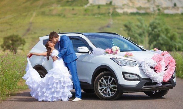 Белый шикарный "Hyundai SantaFe" на фоне зеленых холмов и лугов, украшенный бело- розовыми экибанами, рядом с молодоженами - фото 3350381 Компания "Босс авто"