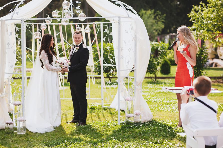 Жених и невеста, взявшись за руки, стоят на фоне белой арки  - фото 3678581 lady_diana