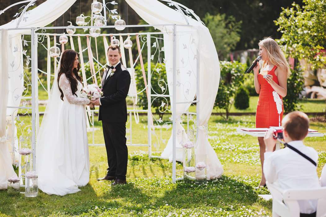 Жених и невеста, взявшись за руки, стоят на фоне белой арки  - фото 3678581 lady_diana
