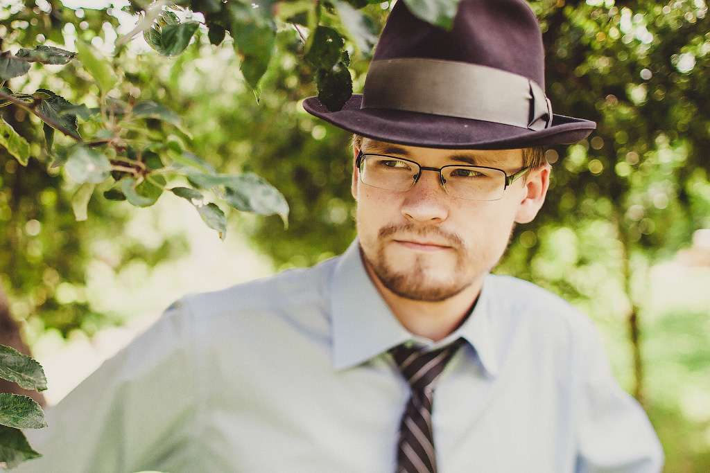Гость на фоне дерева на свадьбе в стиле ретро, в голубой рубашке с галстуком, на голове коричневая шляпа - фото 1350109 Фотограф Гамова Ирина