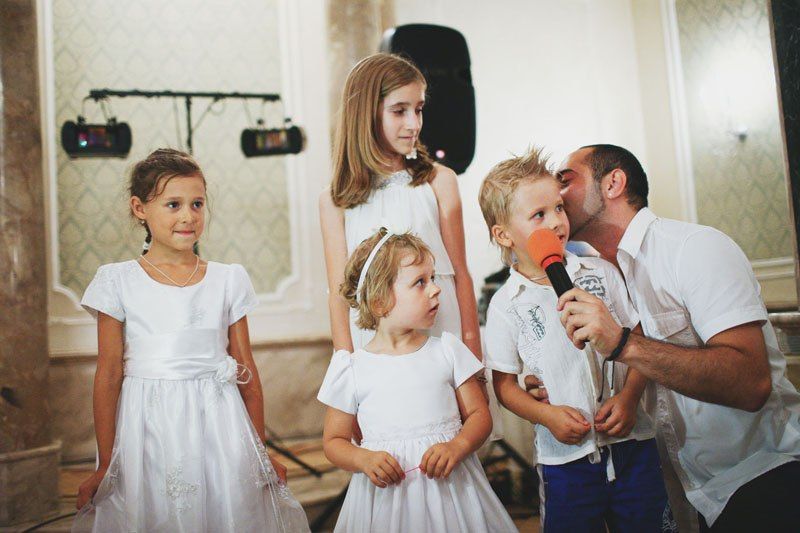 Дети в праздничных нарядах выступают в микрофон перед гостями в праздничном зале - фото 1313551 Свадебный фотограф Александр Кураксин