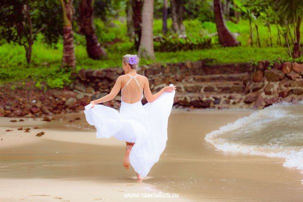 На пляже стоит невеста в открытом длинном платье, руками держит юбку платья  - фото 2832713 Romantica - свадебное агентство в Таиланде