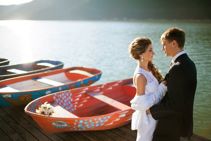 Жених и невеста, прислонившись друг к другу, стоят на фоне лодок и озера - фото 3644993 Фотограф Коломиец Артём
