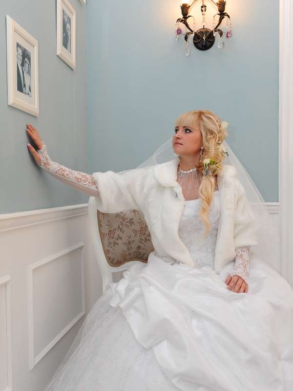 сидящая на стуле невеста разглядывает фотографии на стене - фото 750373 Фотограф Владимир Скранжевский