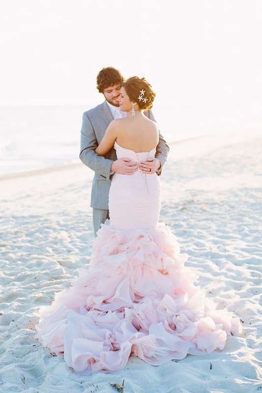  На пляже, стоят обнявшись жених и невеста, она в розовом платье, со шлейфом, он в белой рубашке и в светлом костюме - фото 1542955 elenasperanza