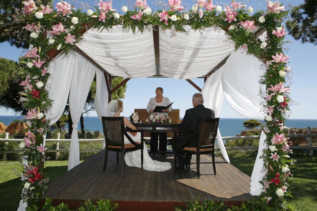 Свадебная арка из живых цветов, драпированная белой тканью, на фоне молодоженов - фото 577729 Algarve Events - свадебное агентство в Португалии