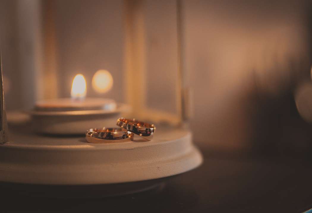 Золотые обручальные кольца, выполнены в классическом стиле на фоне белого фонаря со свечей. - фото 2266978 Lui et Elle photography